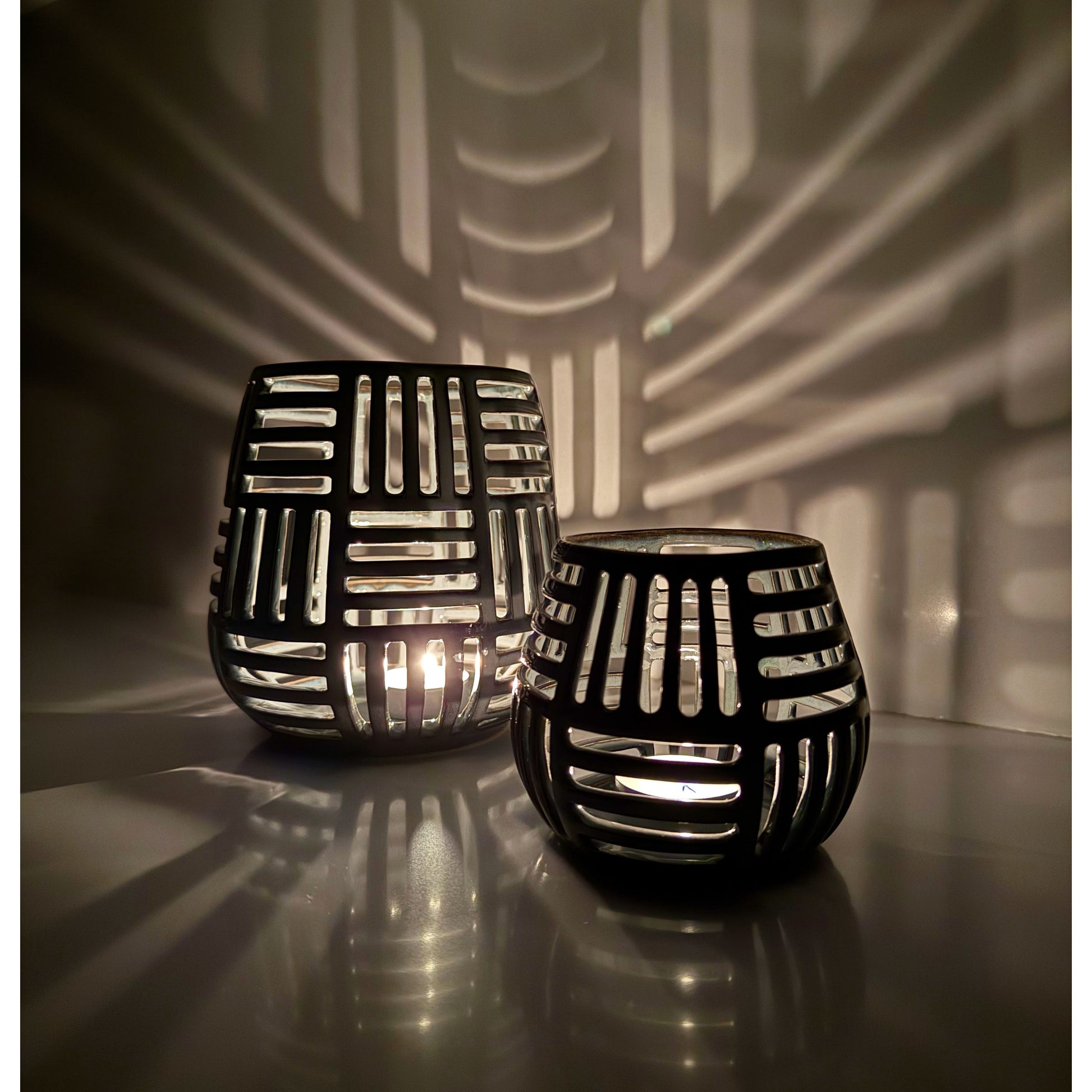 Decorative ceramic lanterns with grid pattern casting shadows on a wall