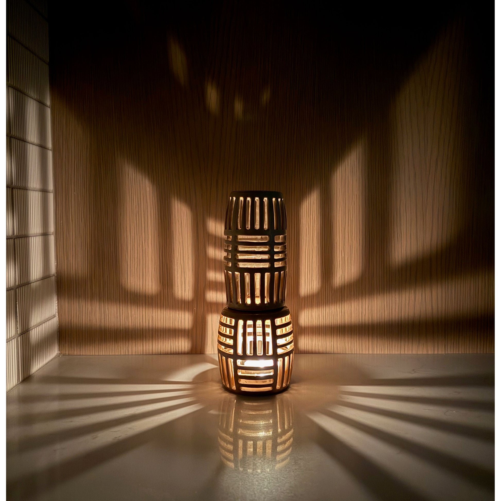 Two stacked woven lanterns casting shadows on a wall.